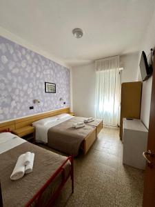 里米尼Hotel Enna Rimini的酒店客房设有两张床和窗户。