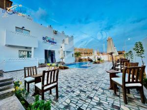 达哈布Dolphina hotel & Restaurant的一个带桌椅的庭院和一个游泳池
