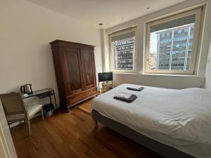 米兰Vittore Rooms & Apartment的一间卧室配有一张床、一个梳妆台和两个窗户。