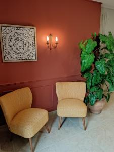 Saint-FulgentHôtel-restaurant Les Colonnades的房间里的两张椅子和一棵植物