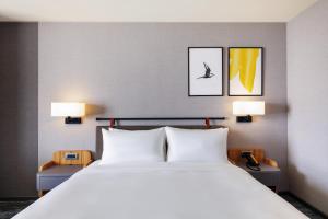 嘉义市voco Chiayi, an IHG Hotel的一间卧室配有一张带两盏灯的大型白色床。