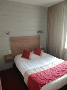 Saint-FulgentHôtel-restaurant Les Colonnades的一间卧室配有一张带两个红色枕头的床