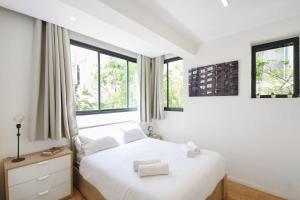 特拉维夫Design 2BR in Dizengoff st by HolyGuest的卧室配有白色的床和2扇窗户。