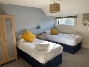 拉特沃思Chequers Country Inn的一间卧室配有两张带黄色枕头的床