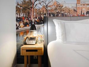 阿姆斯特丹瑞士酒店的一间酒店客房,配有一张床铺和一张桌子上的电话