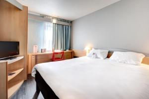 阿让Ibis Agen Centre Gare的酒店客房设有一张白色大床和电视。