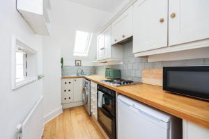 伦敦Stylish Apartment in Putney的厨房配有白色橱柜和木制台面