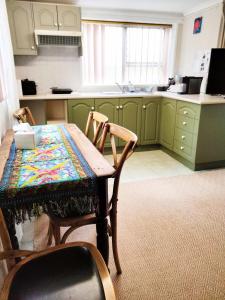 卧龙岗Koloona的厨房配有绿色橱柜和桌椅