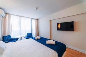 巴统Elite Class Sea View Aparthotel In Orbi City Batumi的酒店客房,配有一张床和两张蓝色椅子