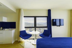 巴统Elite Class Sea View Aparthotel In Orbi City Batumi的客房设有床、两把椅子和窗户。