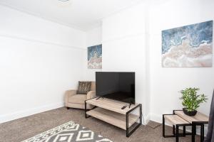 滨海绍森德Large 4 Bed in Southend, near shops/cafés/beach!的一间带电视和沙发的客厅