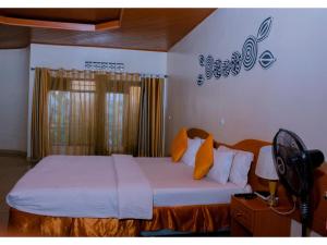 基加利Igitego Hotel Remera的一间卧室配有带白色床单和橙色枕头的床。
