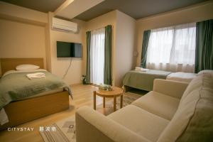大阪CityStay難波南的酒店客房,设有两张床和一张沙发