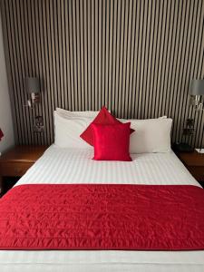 剑桥索伦托酒店&餐厅的一张带红色毯子的床和两个枕头