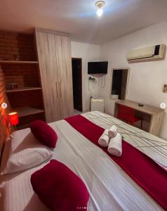奥林达普萨达波巴酒店的一间卧室配有一张带红色和白色枕头的大床