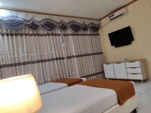 BongomeonH. V Hotel Bandara Gorontalo的酒店客房设有两张床和电视。