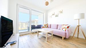 贡斯基Apartamenty Sun & Snow Gąski的客厅配有粉红色的沙发和电视