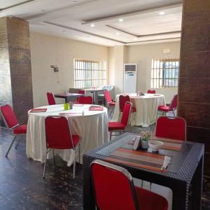科托努HOTEL MAVILLA Cotonou的配有桌子和红色椅子及桌子的房间