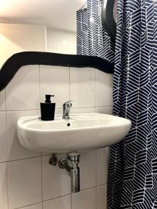 克卢日-纳波卡ALTiDude的浴室设有白色水槽,配有黑色和白色的浴帘