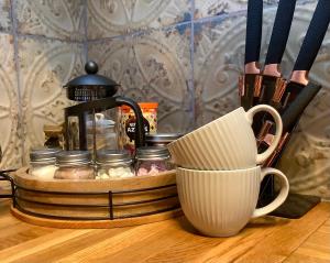 莫法特Holmlea Cottage的一个带咖啡壶的托盘和一张桌子上的杯子