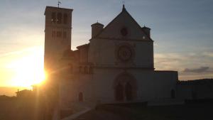 阿西西LE DIMORE ARCANGELO Giuseppe的太阳落在后面的教堂