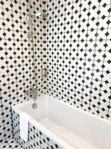 波尔多Hôtel La Tour Intendance的浴室铺有黑白瓷砖,配有白色浴缸。