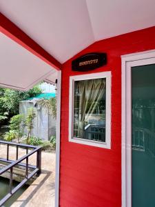 三帕兰MrT Riverside Sampran มิสเตอร์ที โฮมสเตย์-ทองกวาว的一面有窗户的红色房子