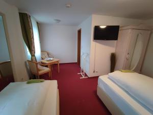 福尔巴赫Room in Guest room - Pension Forelle - Doppelzimmer的客房设有两张床、一张桌子和一台电视机。