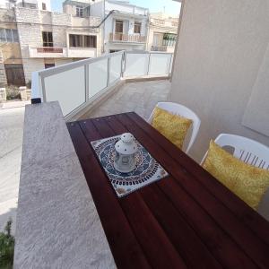 Siġġiewi"Joseph 2" Stylish corner flat with open views, just 5km from the beach的阳台上的木桌和椅子