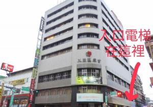 台北黑熊好眠站旅馆 (台北桥店)的一座高大的建筑,前面有红箭