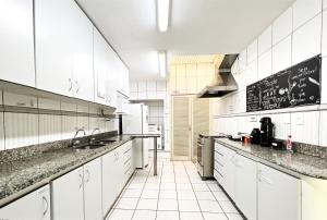 贝洛奥里藏特Br Hostel的厨房配有白色橱柜和墙上的黑板