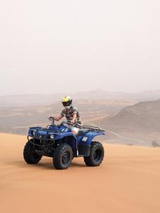 梅尔祖卡Traditional Riad Merzouga Dunes的在沙漠骑四轮摩托车的人