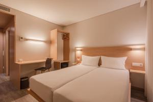 波尔图姆夫波尔图北酒店的卧室配有一张白色大床和一张书桌