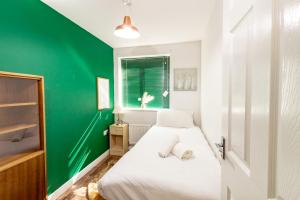 曼彻斯特Spacious 3BR House with Garden & Free Parking的绿色的客房设有一张床和绿色的墙壁