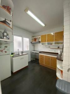 拉科鲁尼亚Apartamento Maresia的一间配备了白色家电和木制橱柜的大厨房