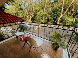普拉亚卡门Che Suites Playa Adults Only的阳台配有2把椅子和桌子,树木繁茂