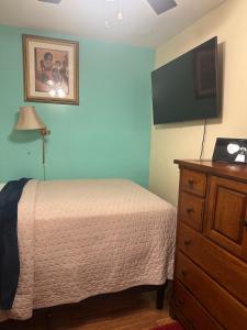 泽西市Genevieve’s comfort pad的一间卧室配有一张床和一个带平面电视的梳妆台。