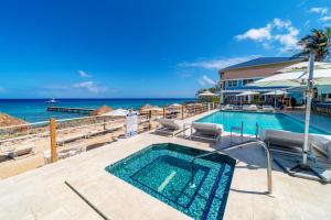 西湾Cobalt Coast Resort的一个带椅子的游泳池,背景是大海