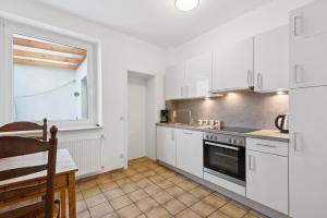 戈赫City-Wohnung direkt am Markt的厨房配有白色橱柜、桌子和窗户。
