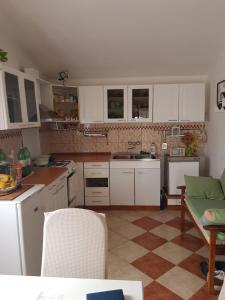 萨利Holiday Home Nada的厨房配有白色橱柜和瓷砖地板。