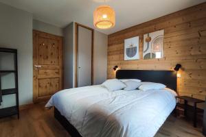 瓦尔莫雷尔CHALET LUMI - Chalet CHALET MAGDALENA pour 6 Personnes 624的卧室配有一张白色大床和木墙