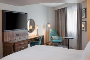 伦敦伦敦切尔西希尔顿逸林酒店的酒店客房配有一张床和一张书桌及一台电视