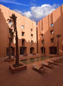BenguerirDoubletree By Hilton Ben Guerir Hotel & Residences的一座带庭院的建筑,庭院内设有游泳池和棕榈树