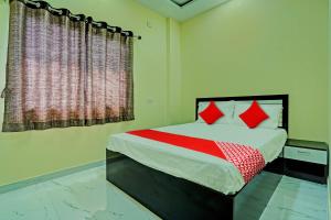 RāipurOYO Flagship Hotel Bliss Inn的一间卧室配有一张带红色枕头的床和一扇窗户