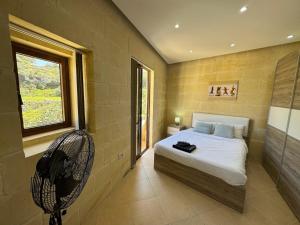 Għajn il-KbiraThe Nest Siekel Townhouse的一间卧室配有一张带风扇和窗户的床。