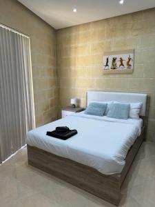 Għajn il-KbiraThe Nest Siekel Townhouse的一间卧室配有一张带白色床单和蓝色枕头的大床。