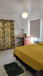 迈里波朗Pousada Pitoresca的一间卧室配有黄色的床、一张桌子和一面镜子