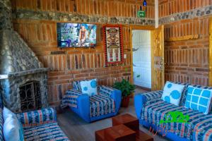科塔卡奇Watzara Wasi Cottage Familiar Camprestre Y Lofts en Cotacachi的客厅配有2把蓝色椅子和电视