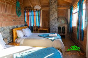 科塔卡奇Watzara Wasi Cottage Familiar Camprestre Y Lofts en Cotacachi的一间卧室设有两张床和一个壁炉