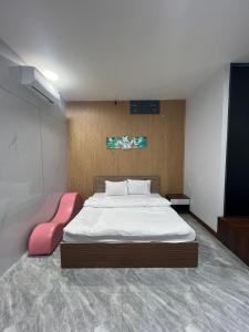 Ðịnh HòaThành Phố Mới Hotel的一间卧室配有一张大床和一张粉红色的椅子